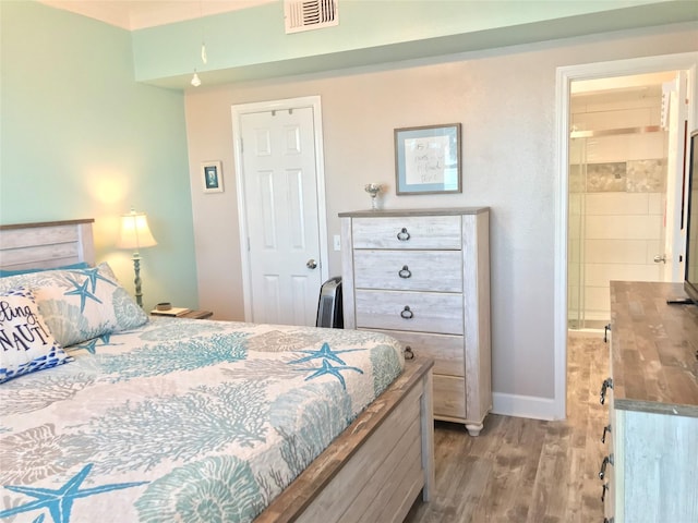 bedroom with ensuite bathroom and light wood-type flooring