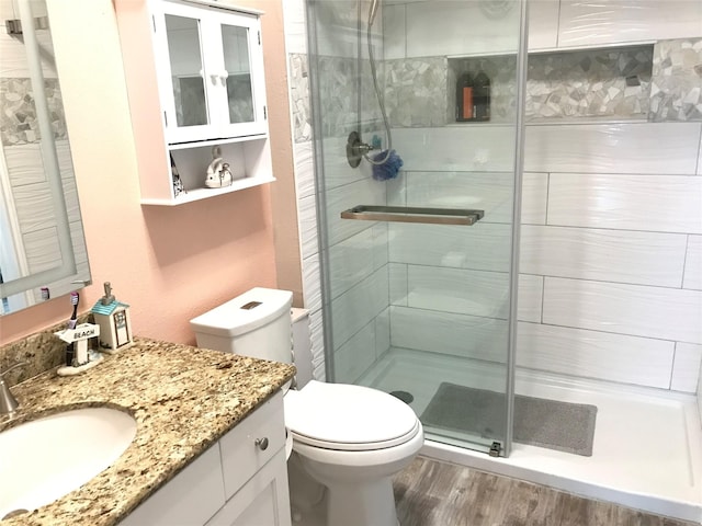 bathroom with vanity, a shower with shower door, hardwood / wood-style floors, and toilet