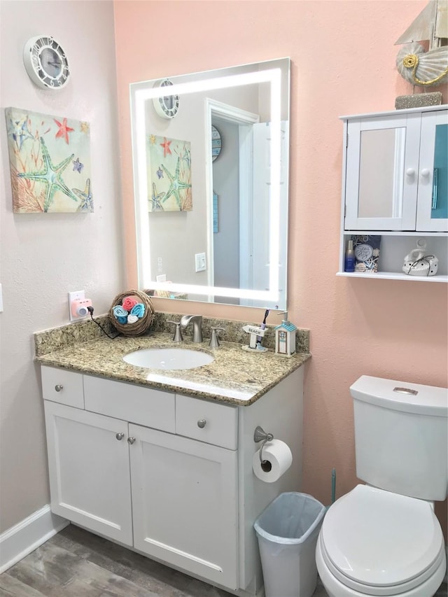 bathroom with hardwood / wood-style flooring, vanity, and toilet