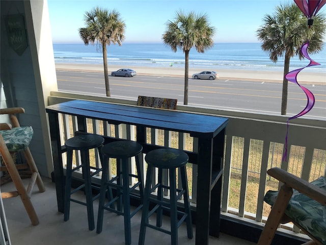 balcony with a view of the beach, a bar, and a water view