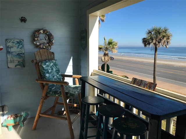 balcony with a water view and a view of the beach