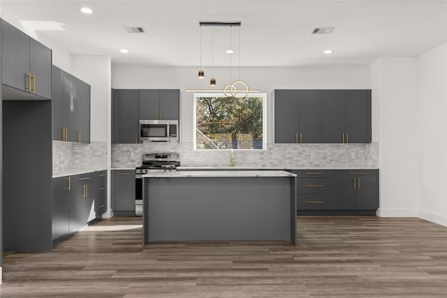 kitchen featuring pendant lighting, a kitchen island, gray cabinets, and appliances with stainless steel finishes