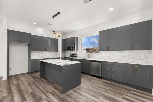 kitchen with pendant lighting, gray cabinets, appliances with stainless steel finishes, dark hardwood / wood-style floors, and a center island