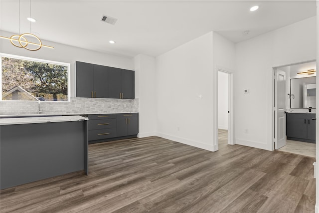 kitchen with tasteful backsplash, dark hardwood / wood-style floors, decorative light fixtures, and gray cabinetry