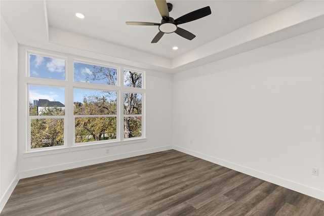 spare room with ceiling fan, dark hardwood / wood-style floors, and a raised ceiling