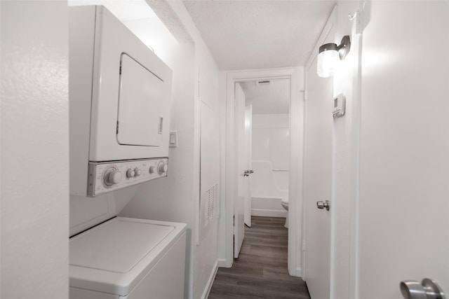 clothes washing area with stacked washer / drying machine, dark hardwood / wood-style flooring, and a textured ceiling