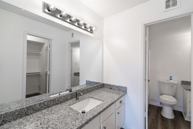 bathroom featuring vanity, toilet, hardwood / wood-style floors, and a textured ceiling