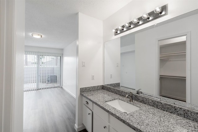 bathroom featuring hardwood / wood-style flooring, vanity, and a textured ceiling