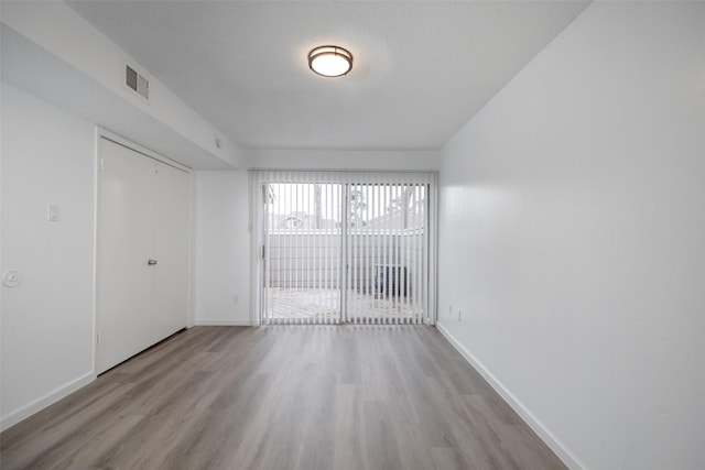 unfurnished room with light hardwood / wood-style flooring and a textured ceiling