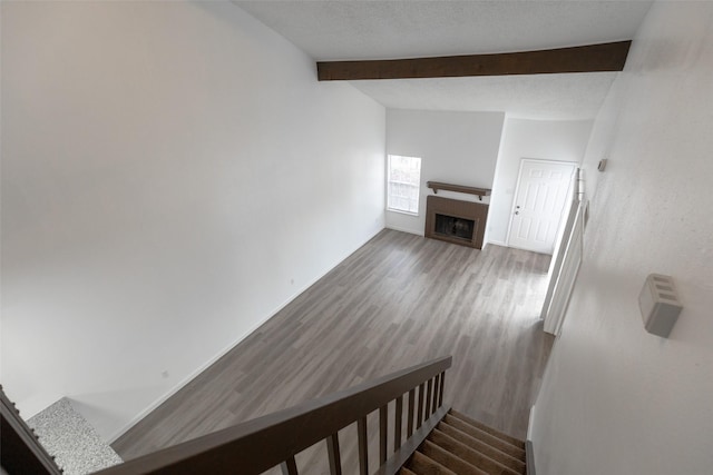 staircase with lofted ceiling with beams, wood-type flooring, and a textured ceiling