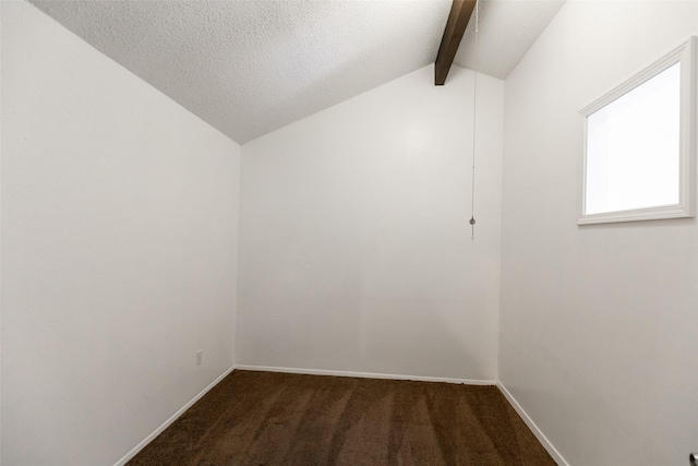 empty room with dark carpet, lofted ceiling with beams, and a textured ceiling