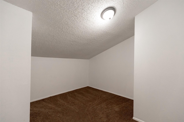 additional living space featuring lofted ceiling, a textured ceiling, and dark colored carpet