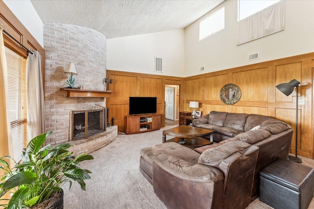 carpeted living room with a brick fireplace, high vaulted ceiling, a textured ceiling, and wood walls