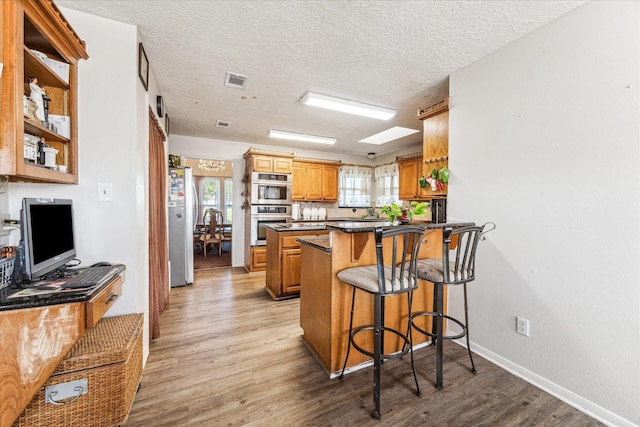 kitchen featuring light hardwood / wood-style flooring, a breakfast bar, plenty of natural light, stainless steel appliances, and kitchen peninsula