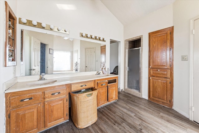 bathroom featuring walk in shower, lofted ceiling, wood-type flooring, and vanity