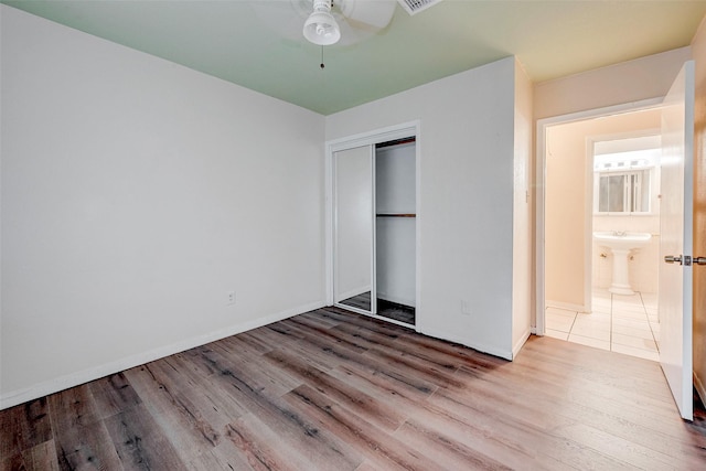 unfurnished bedroom featuring sink, hardwood / wood-style flooring, a closet, and ceiling fan