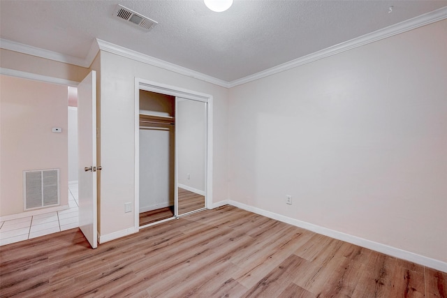 unfurnished bedroom with crown molding, a textured ceiling, and light hardwood / wood-style floors