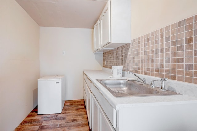 kitchen with white cabinetry, sink, backsplash, fridge, and light hardwood / wood-style floors