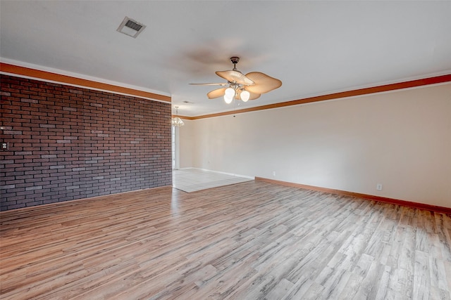 empty room featuring crown molding, brick wall, ceiling fan, and light wood-type flooring