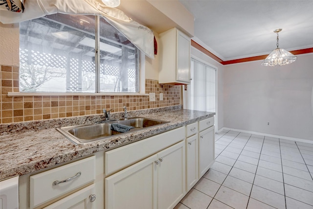 kitchen featuring sink, white cabinetry, ornamental molding, decorative backsplash, and decorative light fixtures