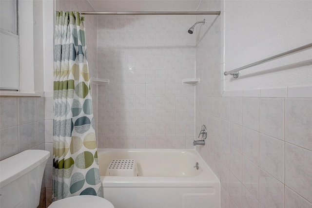 bathroom featuring tile walls, shower / tub combo, and toilet