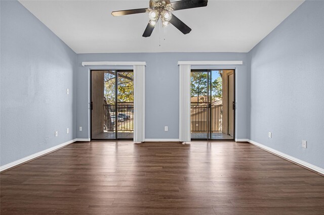 empty room featuring healthy amount of natural light, dark wood-style flooring, ceiling fan, and baseboards