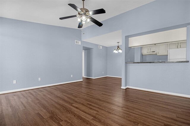 unfurnished living room featuring dark wood finished floors, ceiling fan, baseboards, lofted ceiling, and a chandelier