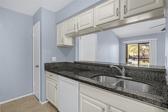 kitchen with white dishwasher, a sink, dark stone countertops, white cabinetry, and light tile patterned floors