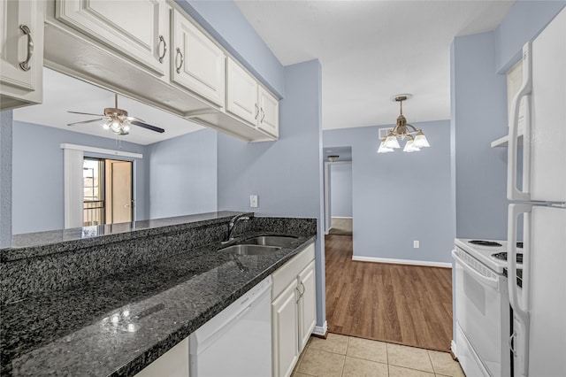 kitchen featuring sink, white appliances, white cabinetry, dark stone countertops, and decorative light fixtures