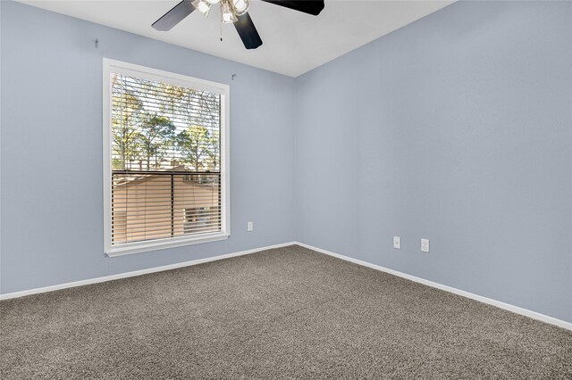 carpeted spare room with a ceiling fan and baseboards