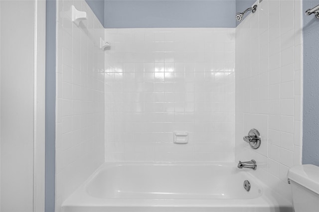 bathroom featuring tiled shower / bath and toilet