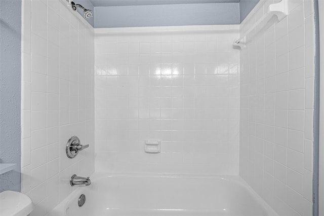 bathroom featuring toilet and tiled shower / bath