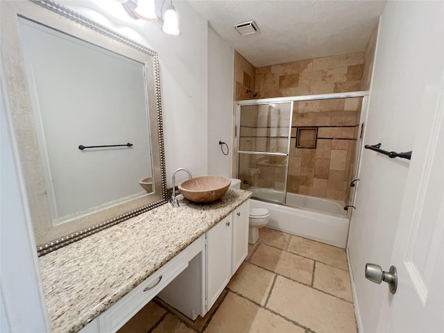 full bathroom with vanity, a textured ceiling, bath / shower combo with glass door, and toilet