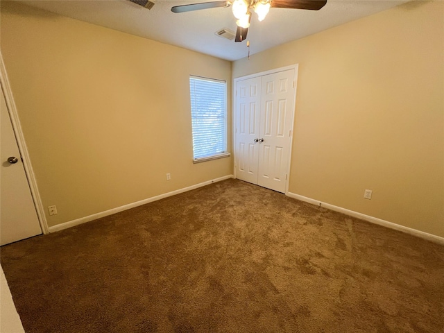 empty room with dark colored carpet and ceiling fan