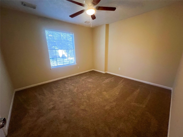 spare room featuring dark carpet and ceiling fan