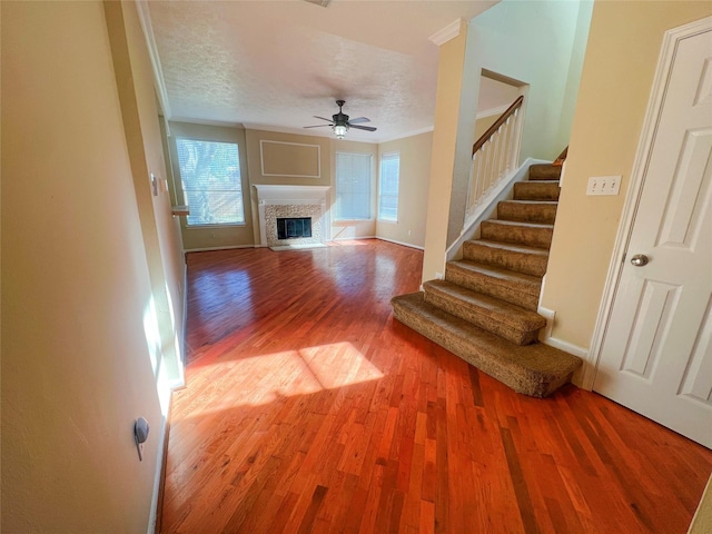 unfurnished living room featuring ceiling fan, hardwood / wood-style floors, and a textured ceiling