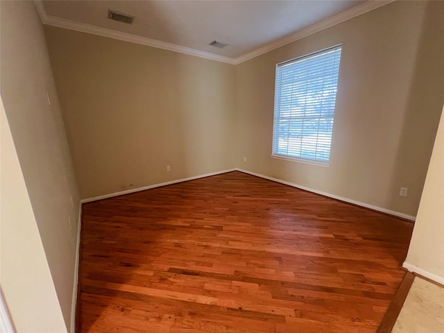 empty room featuring wood-type flooring and ornamental molding