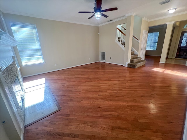 unfurnished living room with ornate columns, ornamental molding, dark wood-type flooring, and a wealth of natural light