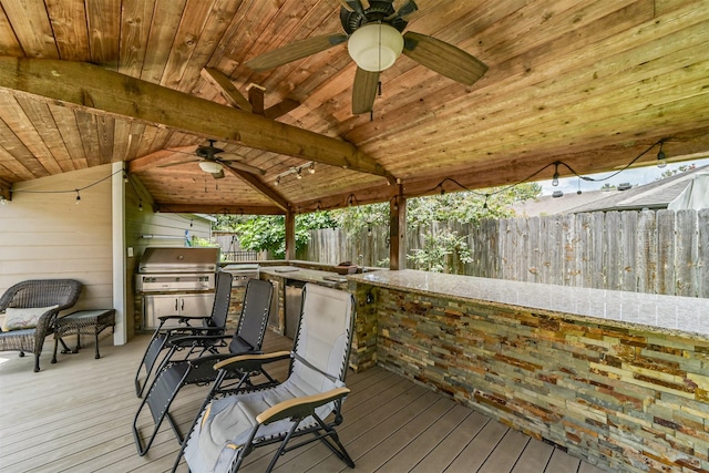 deck featuring grilling area, ceiling fan, and exterior bar