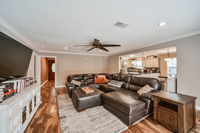 living room featuring crown molding, ceiling fan, and light wood-type flooring