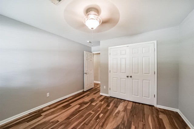 unfurnished bedroom with ceiling fan, dark hardwood / wood-style floors, and a closet