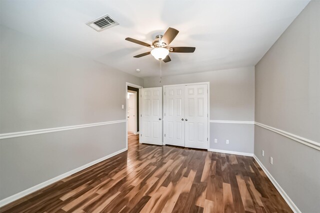 unfurnished bedroom with a closet, dark hardwood / wood-style floors, and ceiling fan