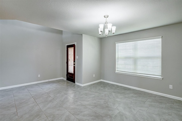 spare room with a textured ceiling and a notable chandelier