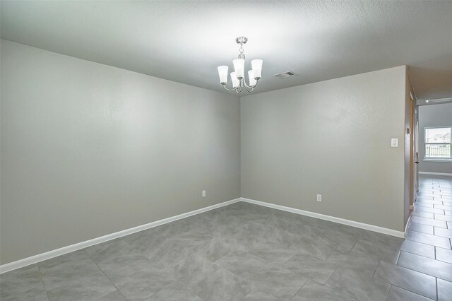 spare room featuring light tile patterned flooring and a chandelier