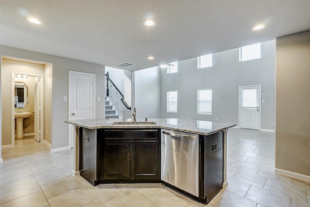 kitchen with dark brown cabinetry, sink, stainless steel dishwasher, and an island with sink