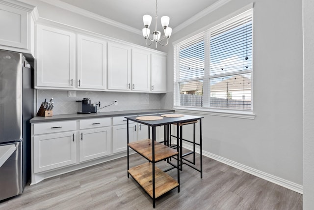 kitchen featuring crown molding, decorative backsplash, stainless steel refrigerator, and white cabinets