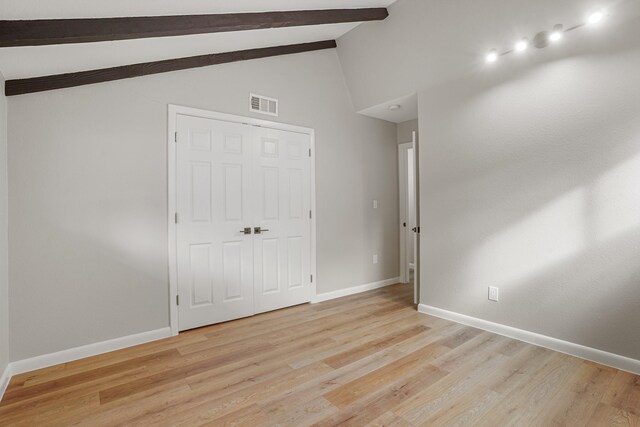 unfurnished bedroom featuring beam ceiling, high vaulted ceiling, a closet, and light wood-type flooring