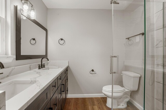 bathroom featuring vanity, hardwood / wood-style flooring, a shower with door, and toilet