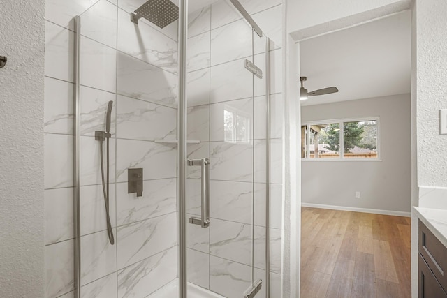 full bathroom featuring vanity, wood finished floors, a marble finish shower, and a ceiling fan