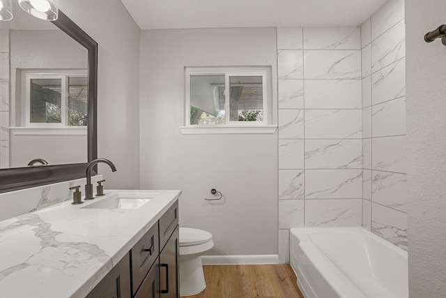 bathroom featuring toilet, vanity, shower / tub combination, wood finished floors, and baseboards